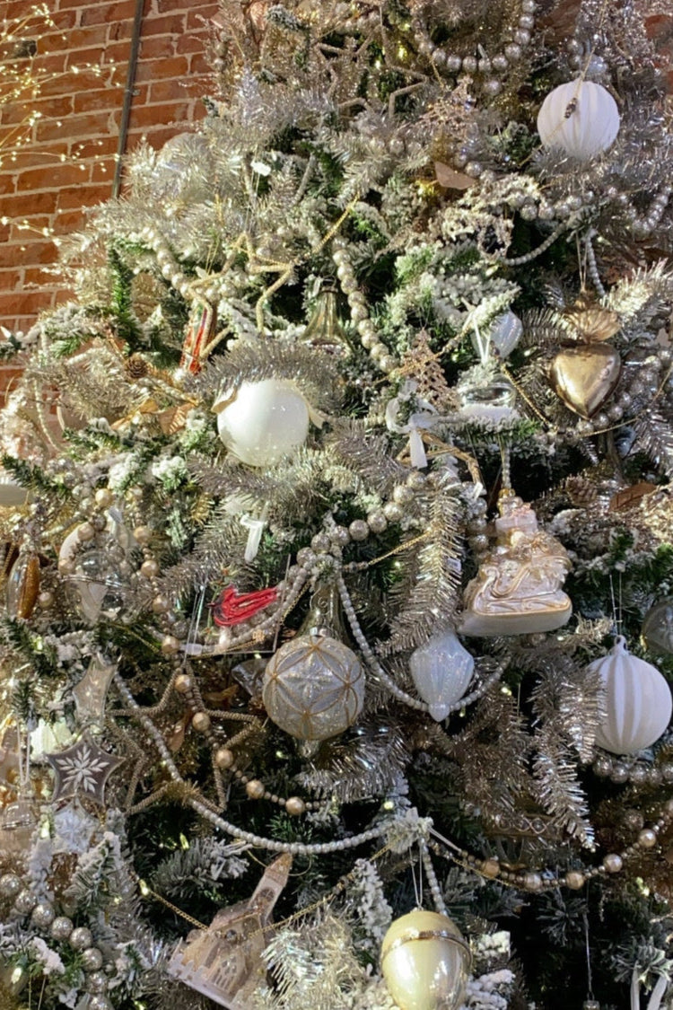 Decorated Christmas tree with ornaments against a brick wall.