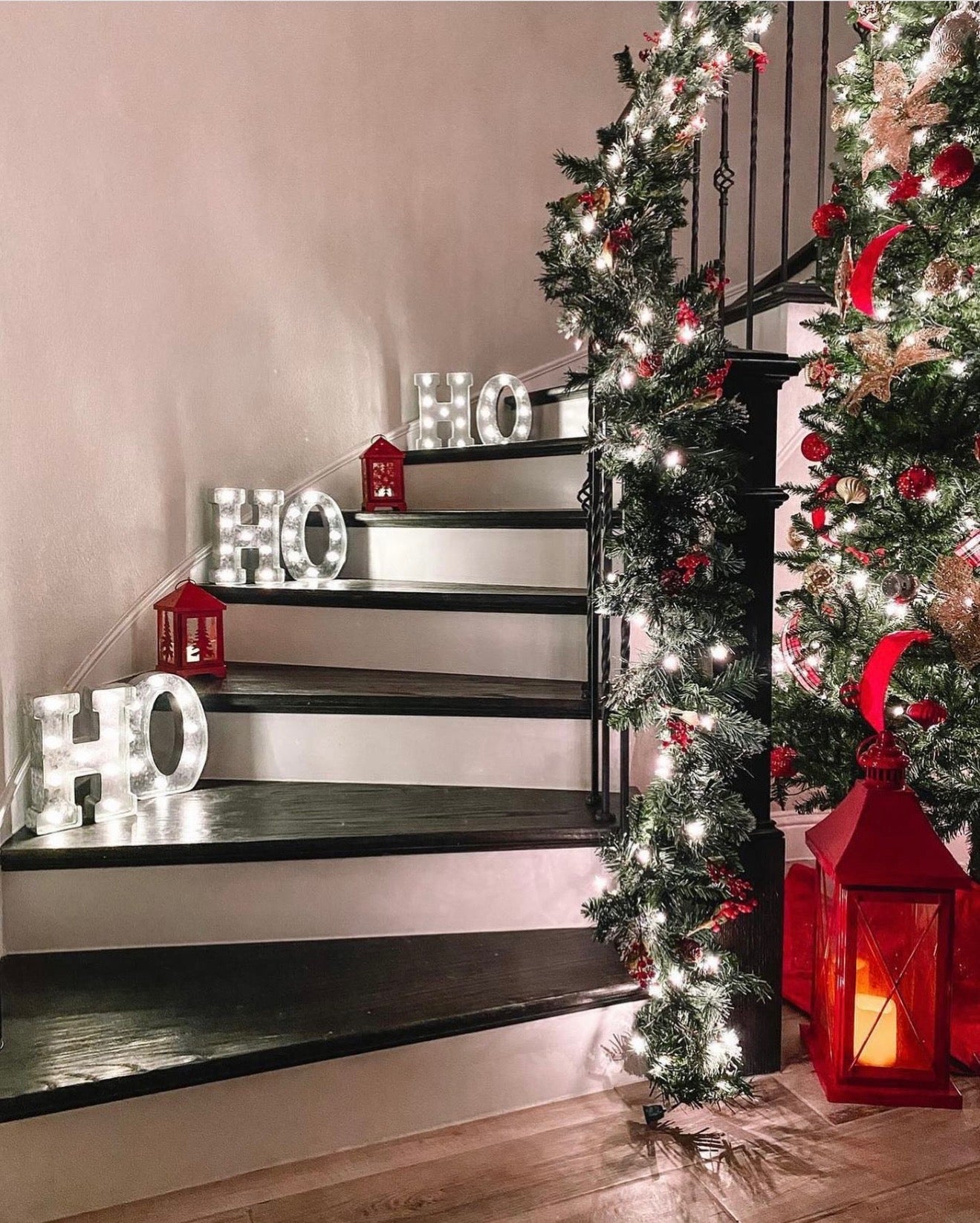 Decorative staircase with Christmas lights, garlands, and a tree.