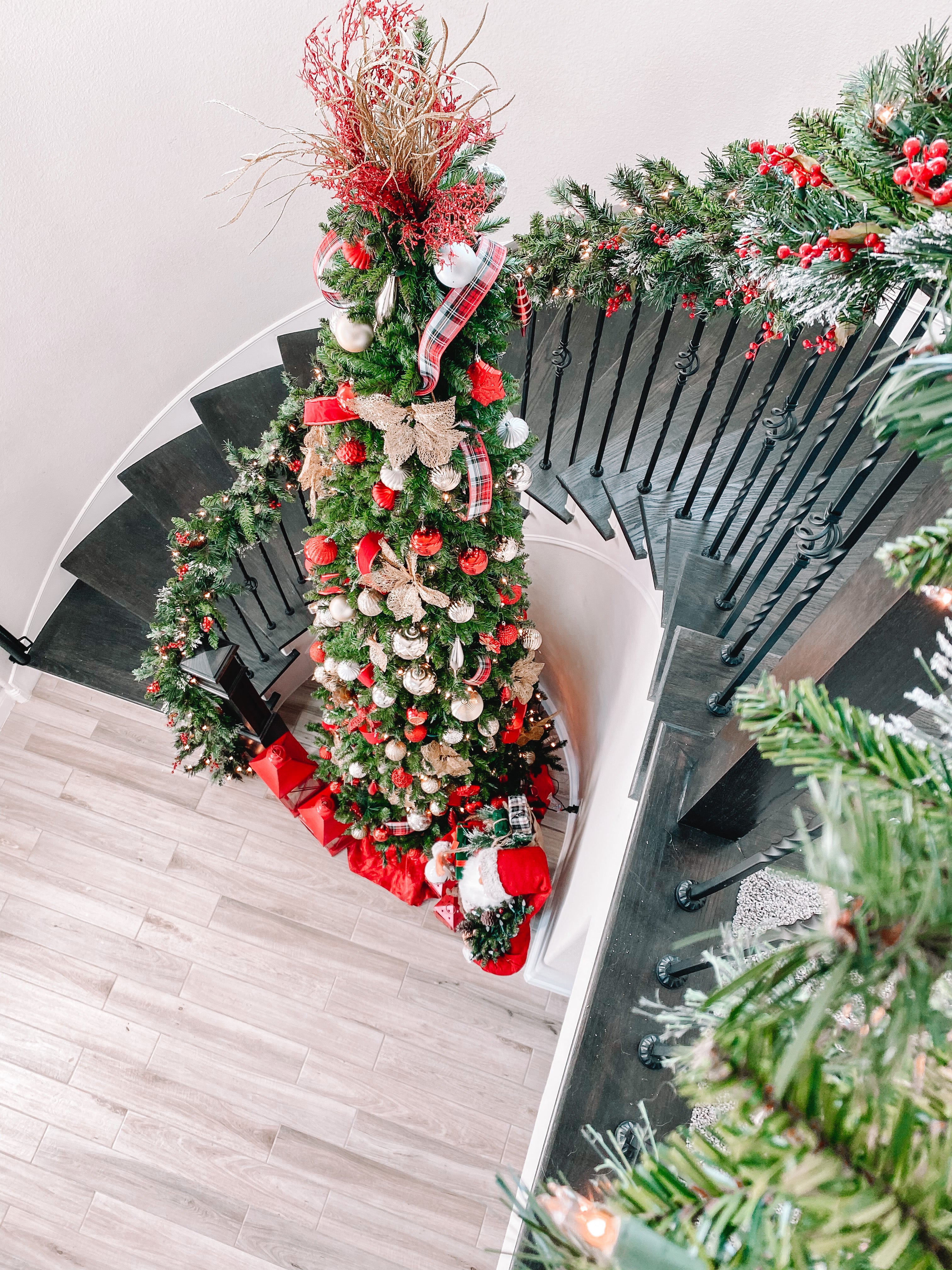 Decorative Christmas tree with red and gold ornaments on a black metal chair.