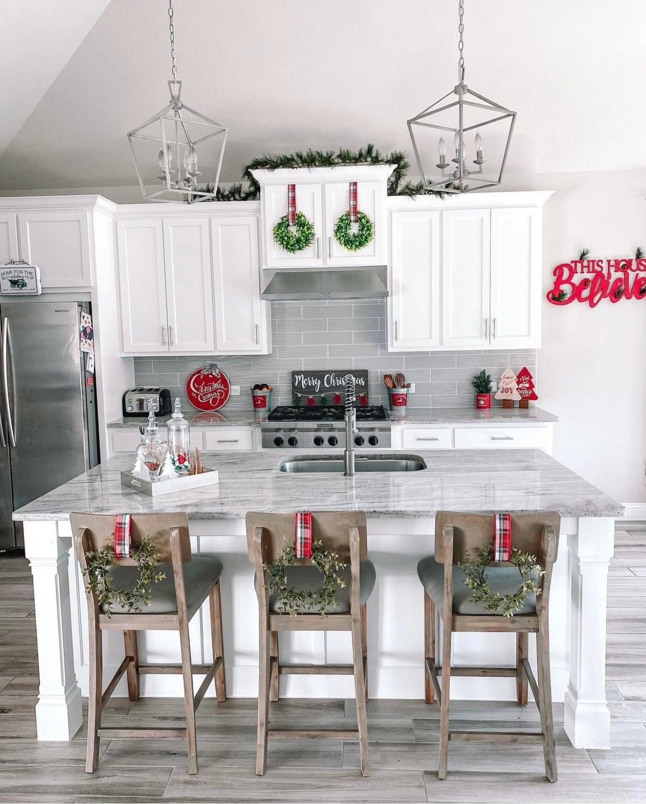 Modern kitchen with white cabinets, marble island, and festive Christmas decorations.